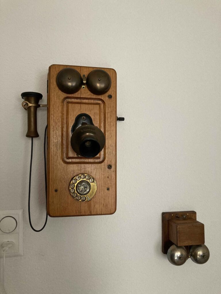 Historische Telefonanlage aus Holz mit Wandhalterung und separater Glocke. 